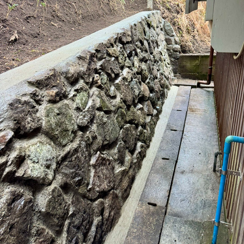 老朽化した石積みの擁壁を解体・補修し、モルタル固定と排水対策で安全性を高めた外構工事の施工事例